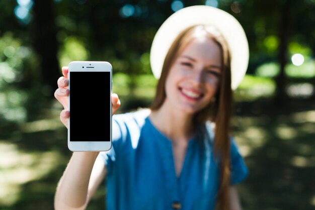 Defocused mujer sosteniendo teléfono inteligente maqueta