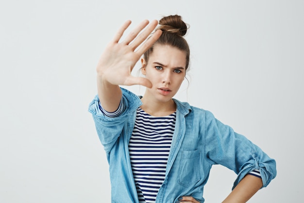 Deja de tomarme fotos. Retrato de mujer europea enojada molesta en ropa de moda tirando de la mano hacia la cámara, tratando de cubrirse del flash, diciendo alto o suficiente