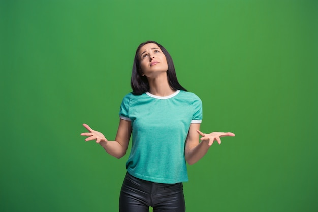 Déjame pensar. Concepto de duda. Mujer pensativa dudosa con expresión pensativa haciendo elección. Joven mujer emocional. Las emociones humanas, el concepto de expresión facial. Frente Estudio. Aislado en verde de moda