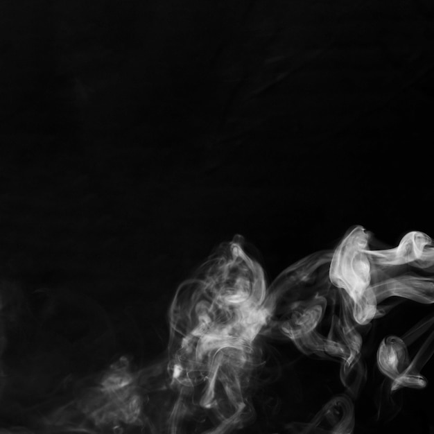 Delicadas olas de humo de cigarrillo blanco sobre fondo negro