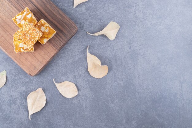 Delicia turca tradicional amarillo con maní sobre tabla de madera sobre fondo gris.