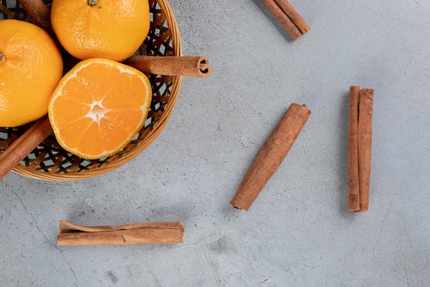 Foto gratuita deliciosa canasta de naranjas con cortes de canela sobre superficie de mármol