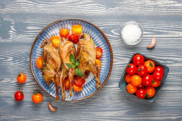 Deliciosa codorniz frita con hierbas y tomates cherry.