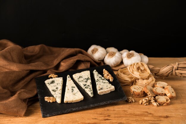 Deliciosa comida artesanal con rodajas de queso y nueces sobre piedra