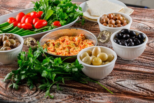 Una deliciosa comida con ensalada, encurtidos en tazones en una olla sobre superficie de madera