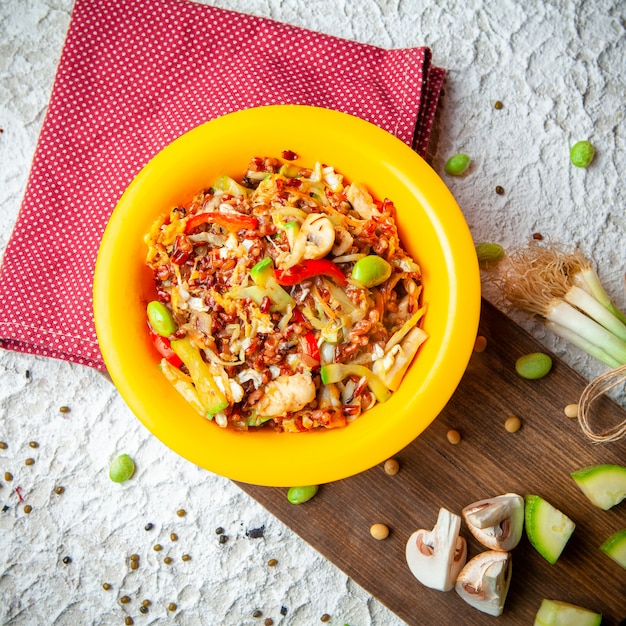 Deliciosa comida en una vista superior de la placa amarilla sobre un fondo de madera, tela roja y textura blanca