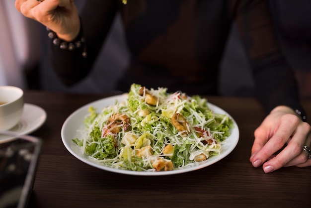 Deliciosa ensalada con crutones; Camarones y queso parmesano rallado en la mesa frente a una persona