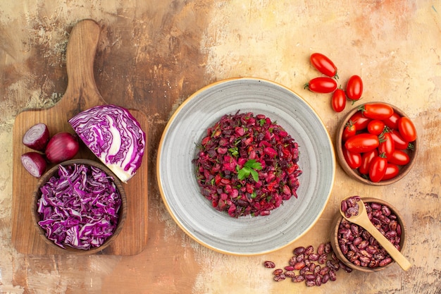 Deliciosa ensalada con remolacha y frijoles y frijoles dentro y fuera de la olla de tomates repollo rojo en la tabla de cortar en la mesa de colores mezclados