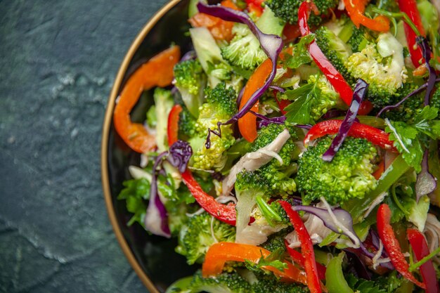 Deliciosa ensalada vegana en un plato con diversas verduras frescas sobre fondo oscuro