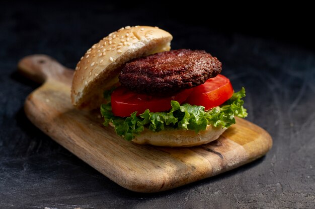 Deliciosa hamburguesa de alto ángulo sobre tabla de madera