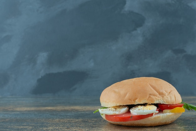 Foto gratuita deliciosa hamburguesa con huevos y tomates sobre fondo de mármol