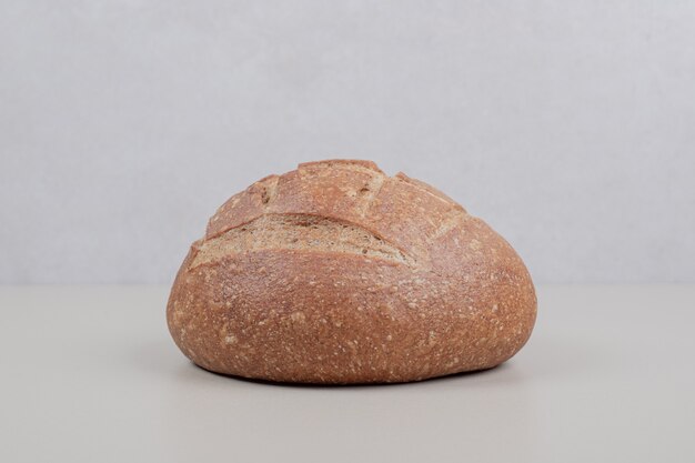 Deliciosa hogaza de pan sobre superficie blanca