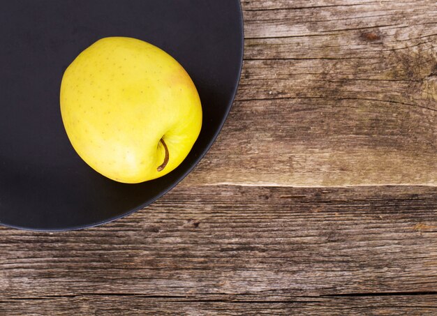 deliciosa manzana en un plato sobre un fondo de mesa de madera