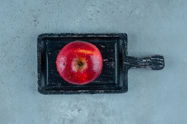 Deliciosa manzana roja en un tablero, sobre el fondo de mármol. Foto de alta calidad