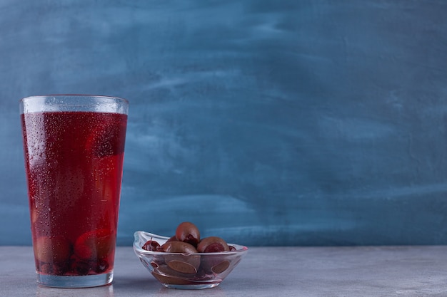 Deliciosa mermelada de frutas con una taza de té negro colocada sobre un fondo de colores.