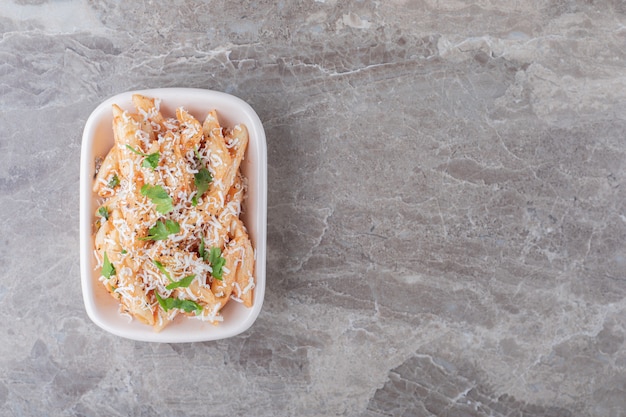 Deliciosa pasta penne en el cuenco, sobre el fondo de mármol.