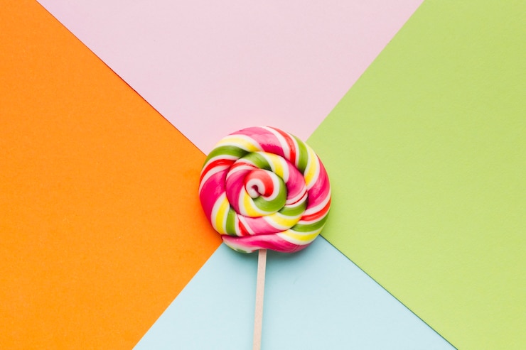 Foto gratuito deliciosa piruleta en mesa colorida