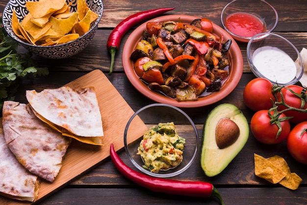 Deliciosa pita junto a la comida entre nachos con salsas y verduras.