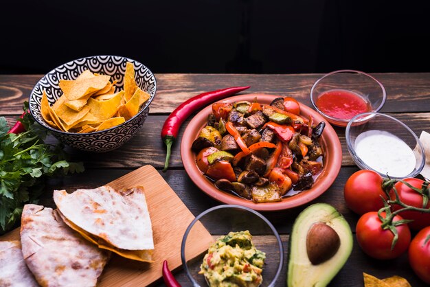 Deliciosa pita junto a la comida entre verduras y nachos.