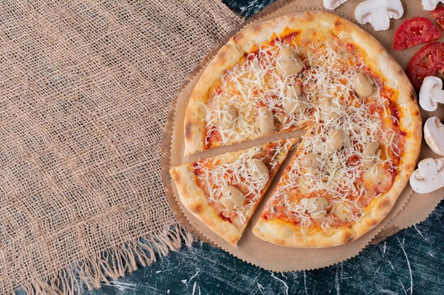 Deliciosa pizza de champiñones con queso y verduras frescas en mármol.