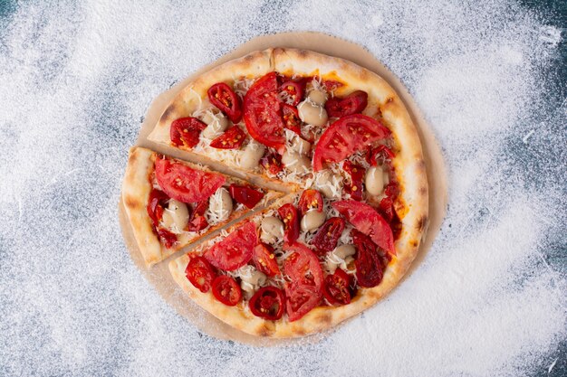 Deliciosa pizza de pollo con tomates en mármol.
