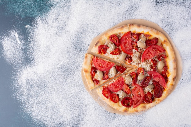 Deliciosa pizza de pollo con tomates en mármol.