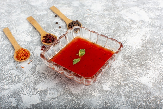 Deliciosa salsa de tomate dentro de la placa de vidrio en gris, comida vegetal para sopa