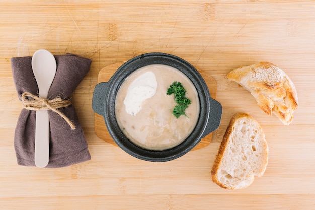 Deliciosa sopa de champiñones con rebanadas de pan; servilleta y cuchara en mesa de madera