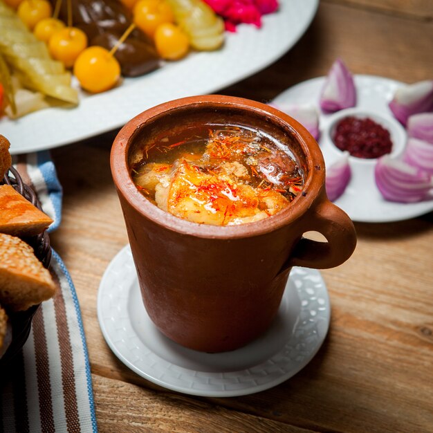 Deliciosa sopa de guisantes orientales con carne en una taza para ir al baño en una mesa de madera. Vista de ángulo alto.