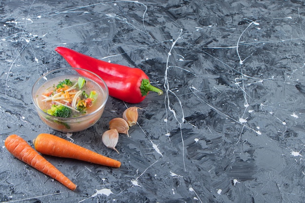 Deliciosa sopa de pollo junto a verduras, sobre el fondo de mármol.