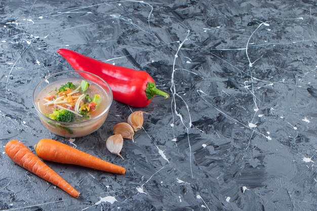 Deliciosa sopa de pollo junto a verduras, sobre el fondo de mármol.