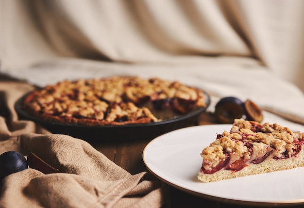 Deliciosa tarta de ciruela con café Chemex e ingredientes con tela sobre una mesa de madera con tela