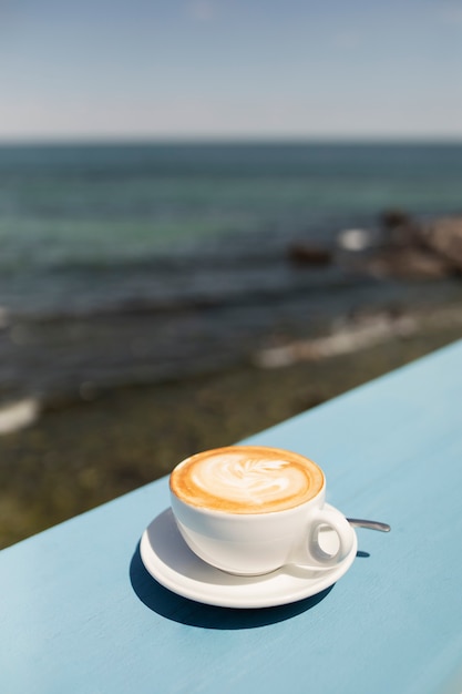 Foto gratuita deliciosa taza de café de alto ángulo en la playa