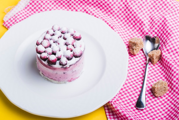 Deliciosas bayas azules en un plato blanco con cubos de azúcar morena y una cuchara con forma de corazón