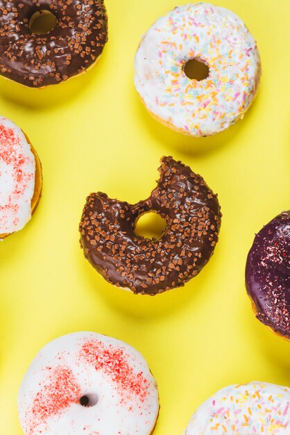 Deliciosas donas con diferentes topping y mordedura de la boca sobre fondo amarillo