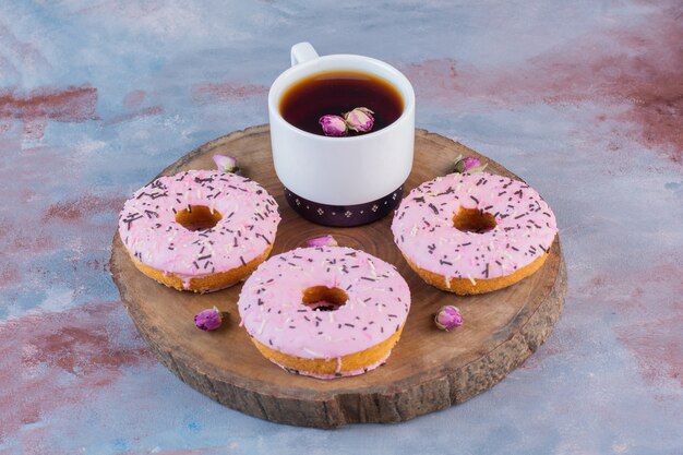 Foto gratuita deliciosas donas con glaseado rosa y una taza de té negro