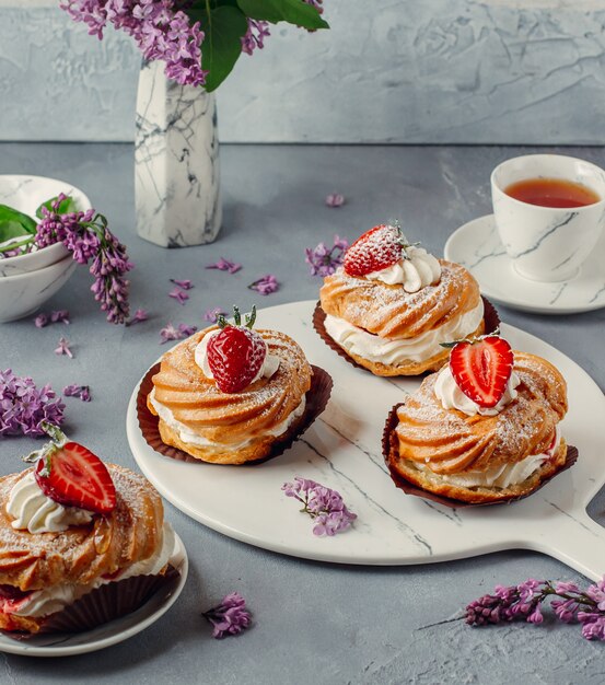 deliciosas eclairs de hojaldre de crema de fresa en tablero de canicas