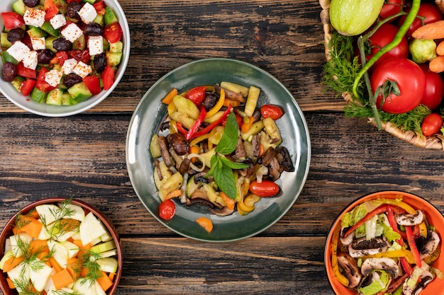 Deliciosas ensaladas de verduras en diferentes tazones en vista superior de la mesa de madera