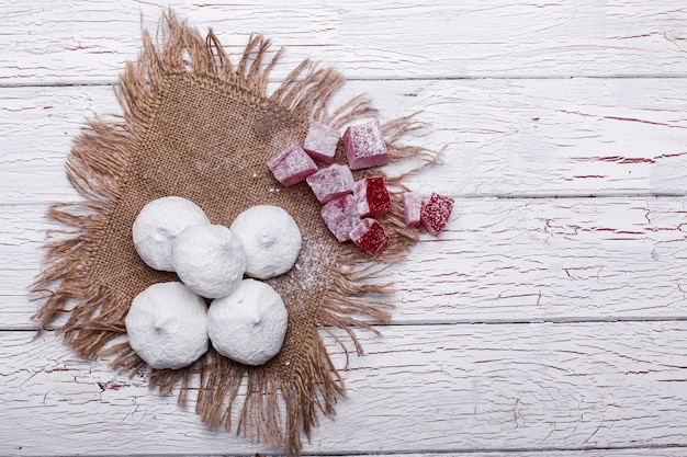 Deliciosas galletas blancas y rojas para el té servido en la mesa de madera blanca