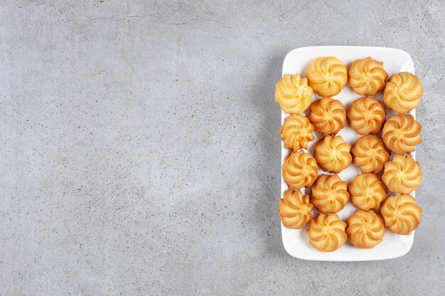 Deliciosas galletas caseras alineadas en un plato sobre fondo de mármol. Foto de alta calidad