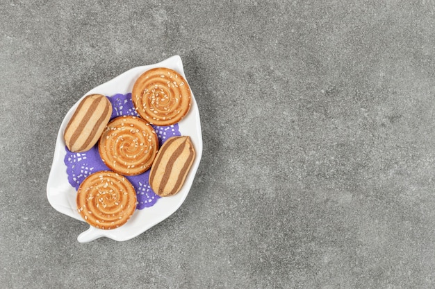 Deliciosas galletas de chocolate a rayas y galletas de sésamo en la placa blanca.