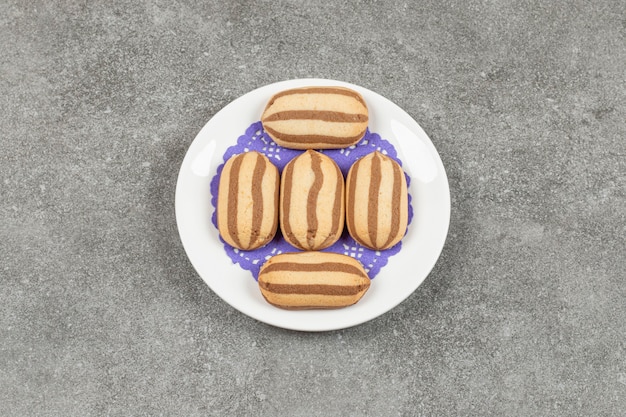 Foto gratuita deliciosas galletas de chocolate a rayas en la placa blanca.