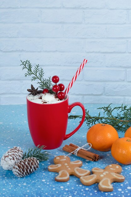 Deliciosas galletas de jengibre, tangeriens y taza de café roja sobre fondo azul. Foto de alta calidad