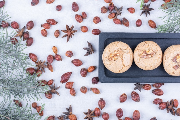 Deliciosas galletas de nuez en un plato oscuro con rosa mosqueta