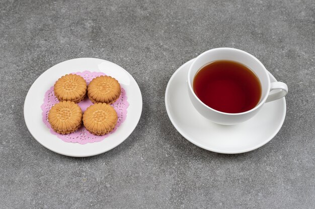 Deliciosas galletas redondas y una taza de té en la superficie de mármol