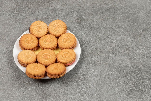 Deliciosas galletas rellenas de crema en la placa blanca.