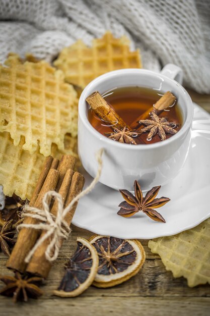 deliciosas galletas y una taza de té caliente con una rama de canela y una cucharada de azúcar morena sobre madera