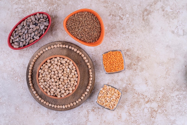 Deliciosas lentejas y frijoles en placas sobre fondo de mármol.