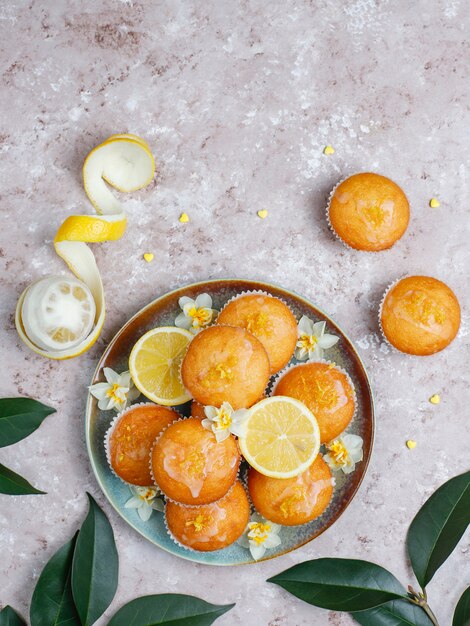 Deliciosas magdalenas caseras de limón recién horneadas con limones en un plato sobre la mesa