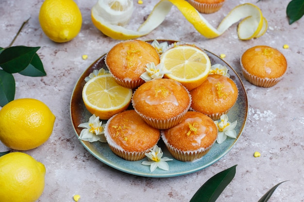 Deliciosas magdalenas de limón caseras recién horneadas con limones en un plato a la luz